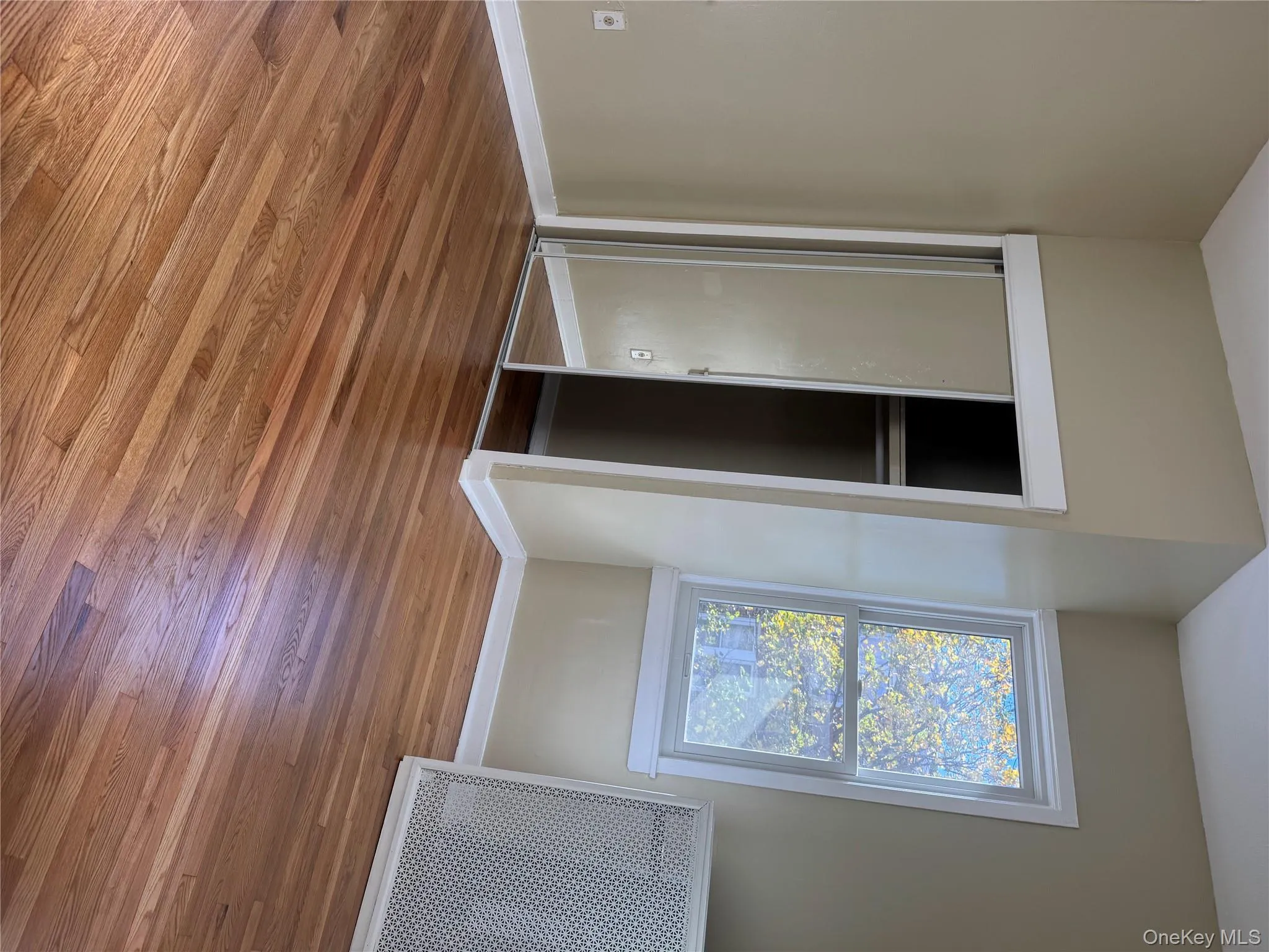 Unfurnished bedroom featuring radiator, wood finished floors, and a closet Unfurnished bedroom featuring radiator, wood finished floors, and a closet