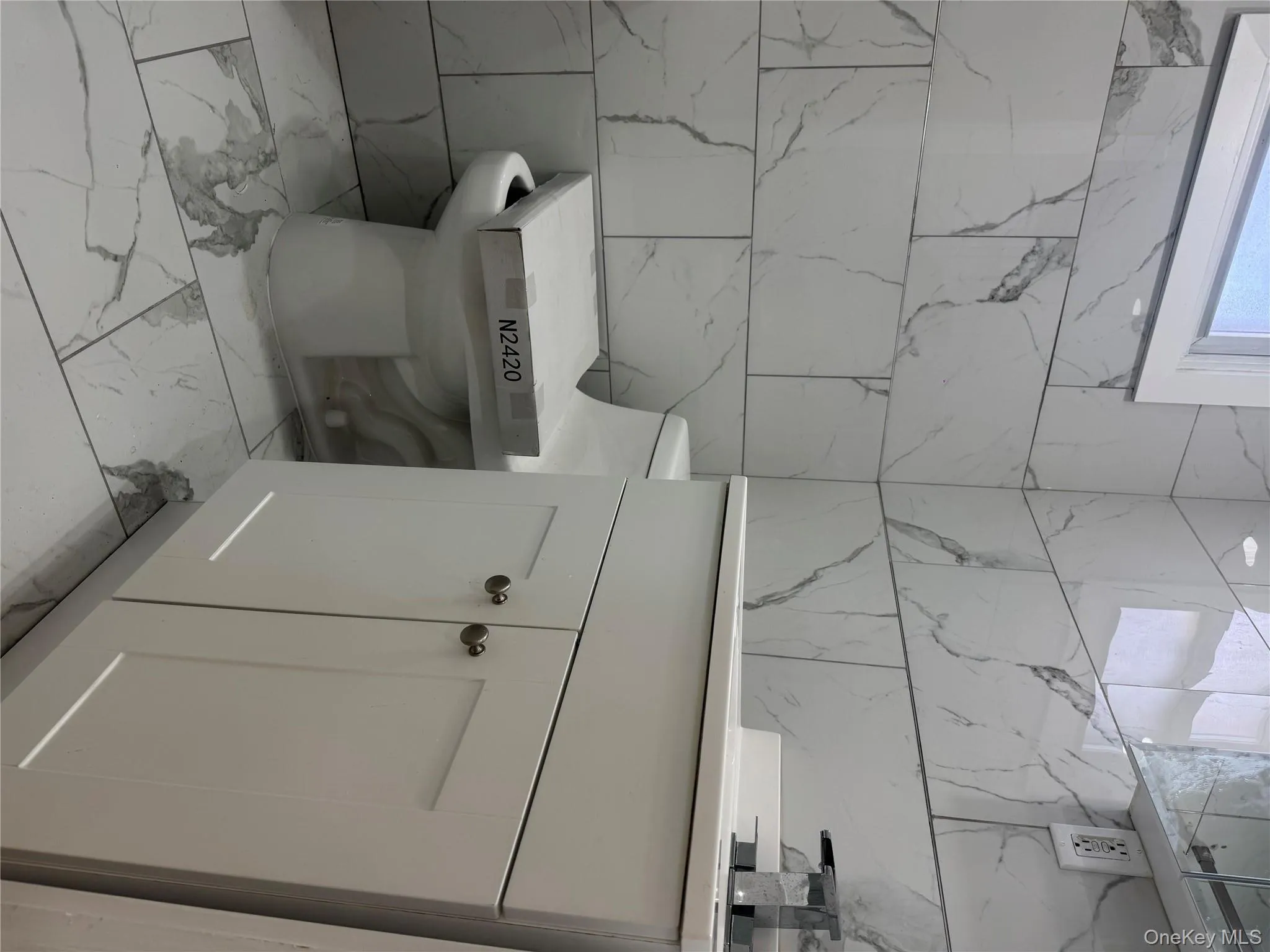Half bath with tile walls, vanity, and light marble finish floors Half bath with tile walls, vanity, and light marble finish floors