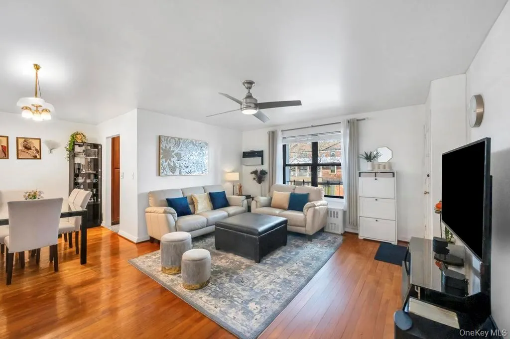 Living room featuring hardwood / wood-style floors, a ceiling fan, and radiator heating unit Living room featuring hardwood / wood-style floors, a ceiling fan, and radiator heating unit