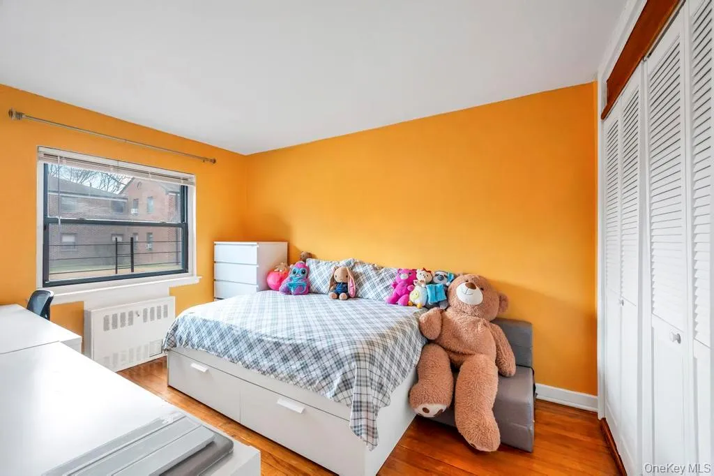 Bedroom featuring radiator heating unit, a closet, and wood finished floors Bedroom featuring radiator heating unit, a closet, and wood finished floors