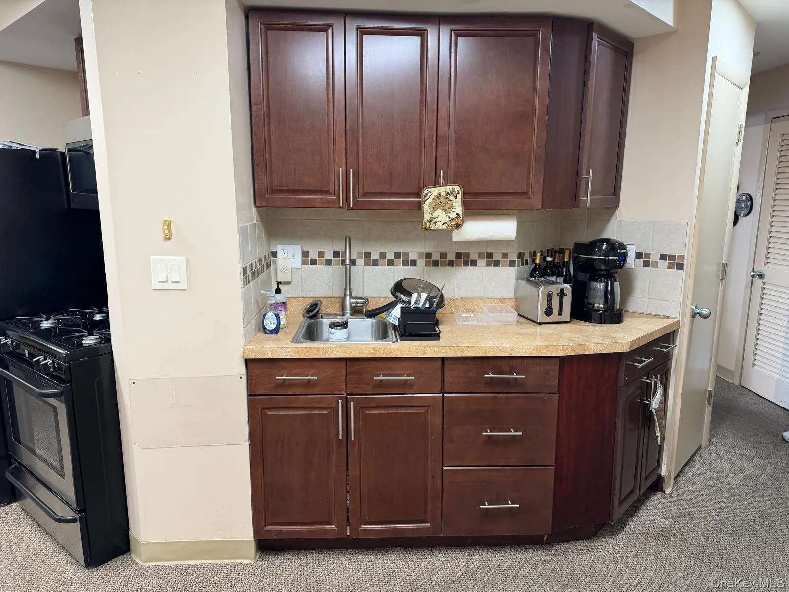 Kitchen with tasteful backsplash, light countertops, stainless steel gas range, and dark brown cabinets Kitchen with tasteful backsplash, light countertops, stainless steel gas range, and dark brown cabinets