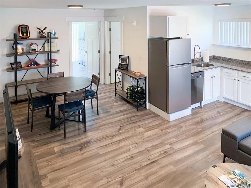 Kitchen with white cabinetry, stainless steel appliances, light wood-style flooring, and dark stone countertops Kitchen with white cabinetry, stainless steel appliances, light wood-style flooring, and dark stone countertops