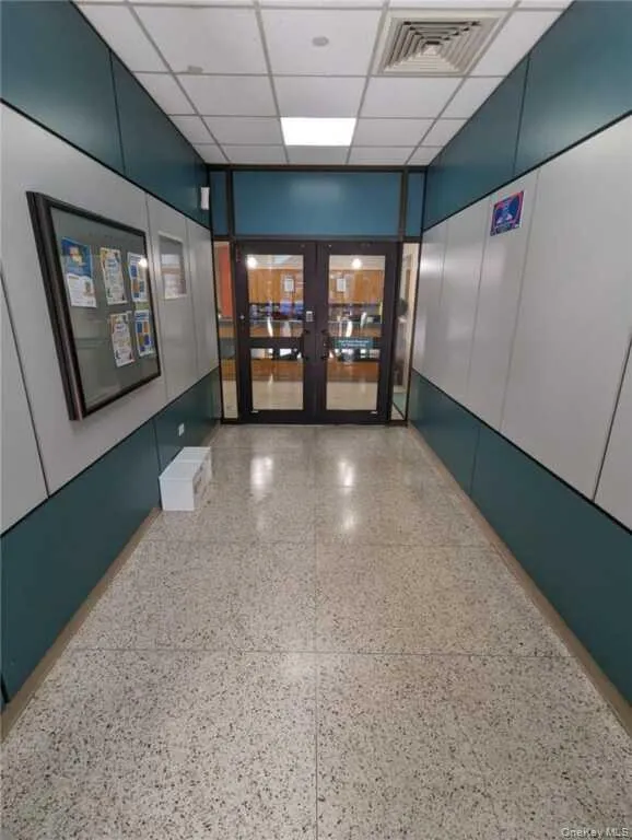 Hall featuring dark speckled floor, a paneled ceiling, and french doors Hall featuring dark speckled floor, a paneled ceiling, and french doors