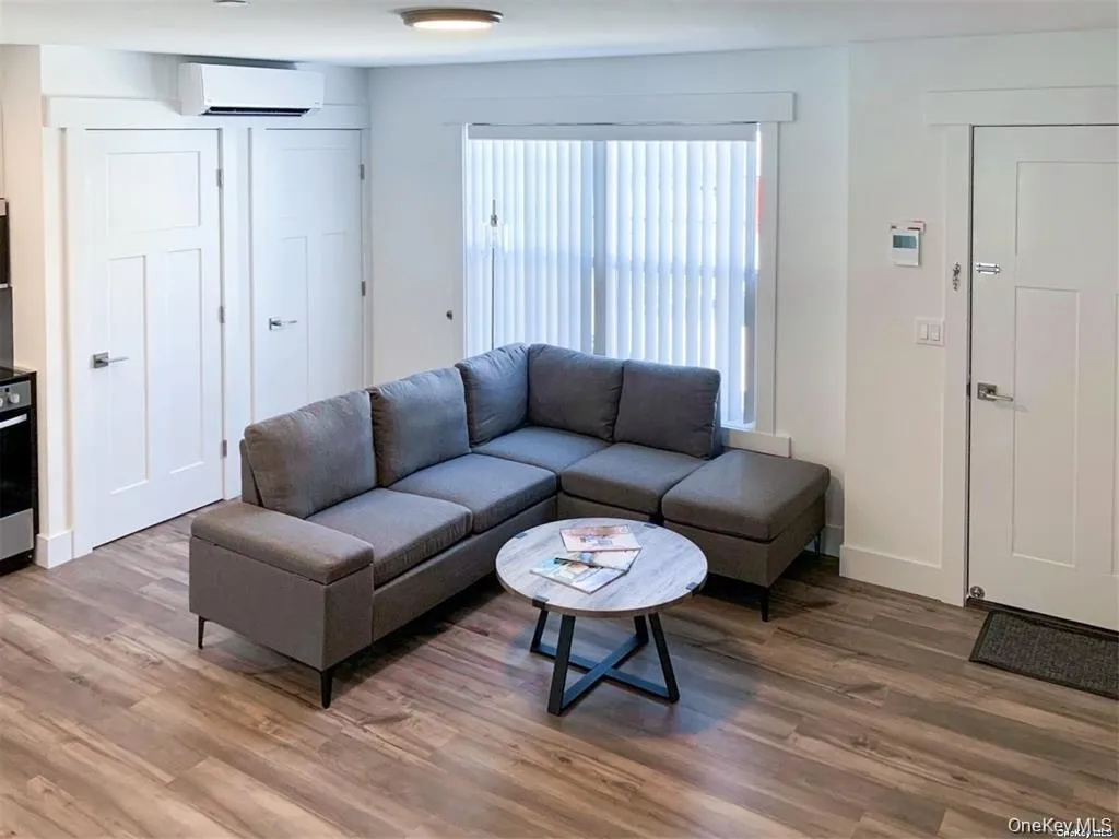 Living area with wood finished floors and a wall mounted AC Living area with wood finished floors and a wall mounted AC