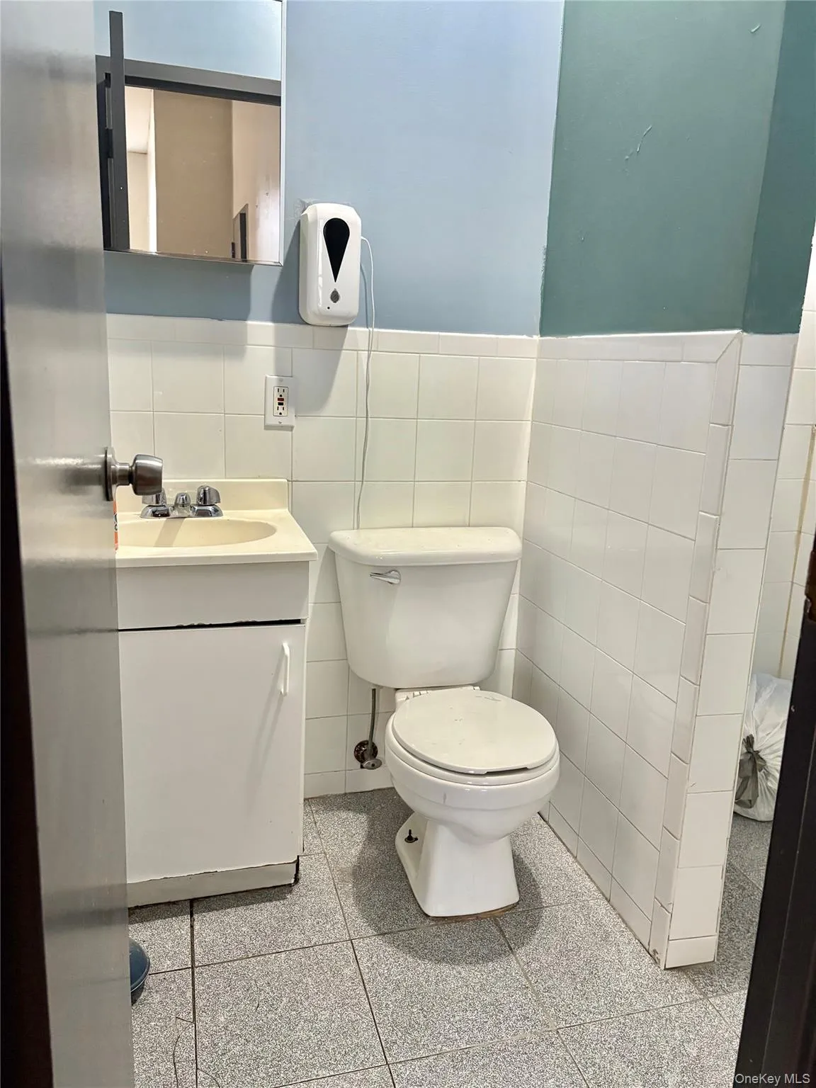 Half bath with vanity, tile walls, and a wainscoted wall Half bath with vanity, tile walls, and a wainscoted wall
