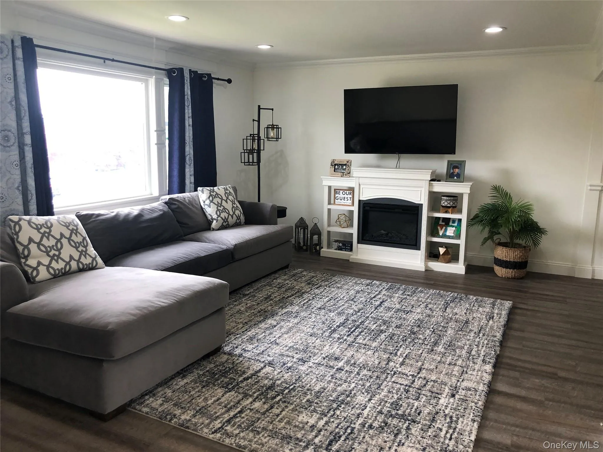 Living area with dark wood-style flooring, a fireplace, ornamental molding, and recessed lighting Living area with dark wood-style flooring, a fireplace, ornamental molding, and recessed lighting