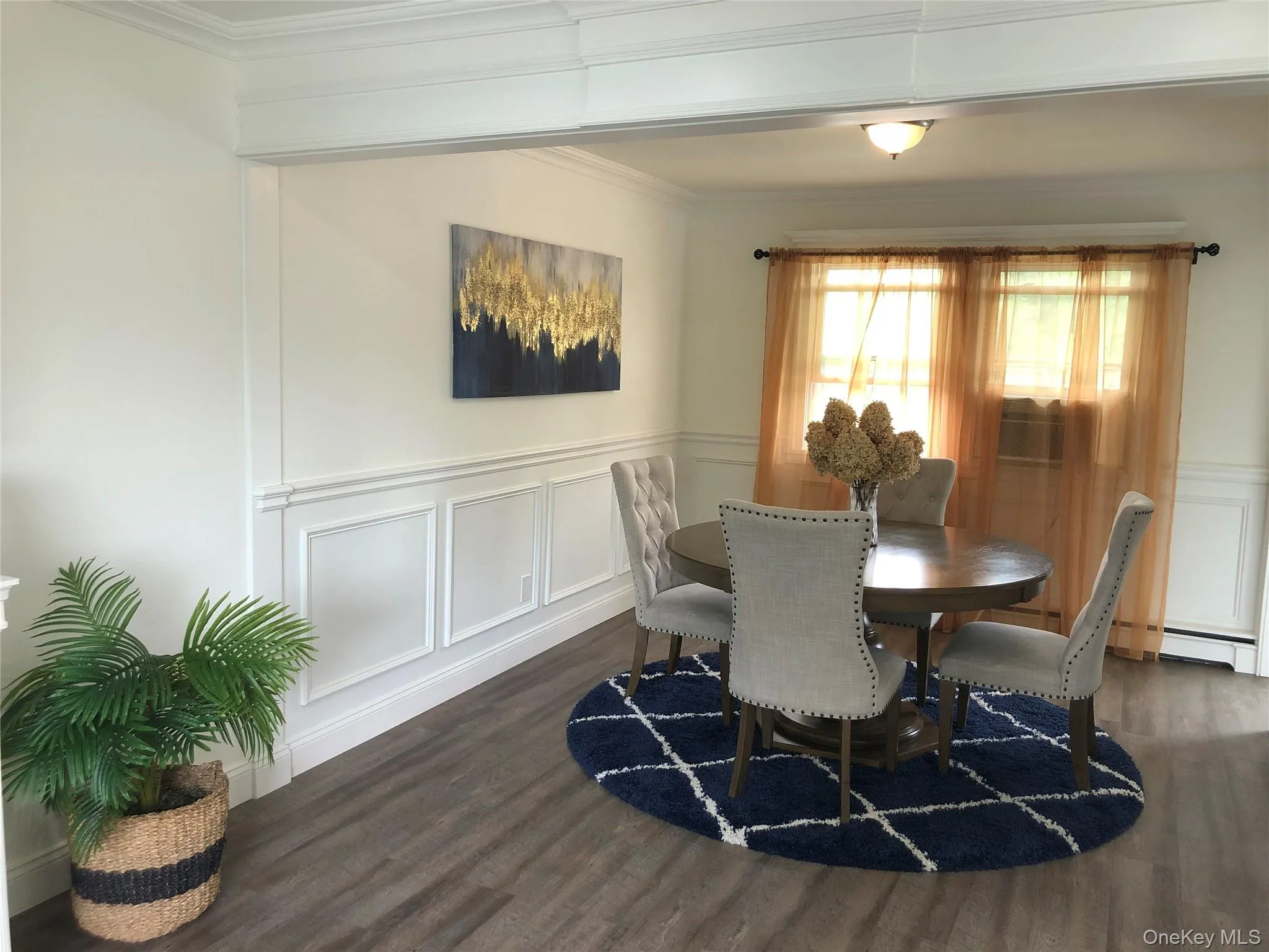 Dining area with a decorative wall, a wainscoted wall, dark wood-style floors, crown molding, and a baseboard heating unit Dining area with a decorative wall, a wainscoted wall, dark wood-style floors, crown molding, and a baseboard heating unit