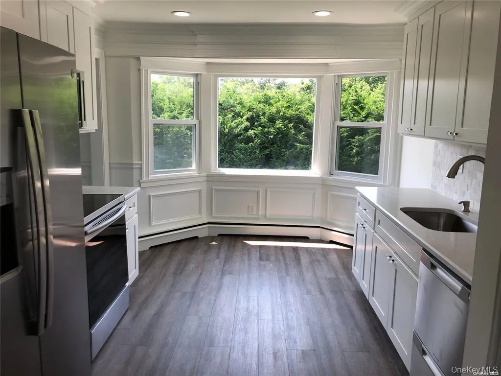 Kitchen featuring appliances with stainless steel finishes, white cabinetry, and light stone counters Kitchen featuring appliances with stainless steel finishes, white cabinetry, and light stone counters