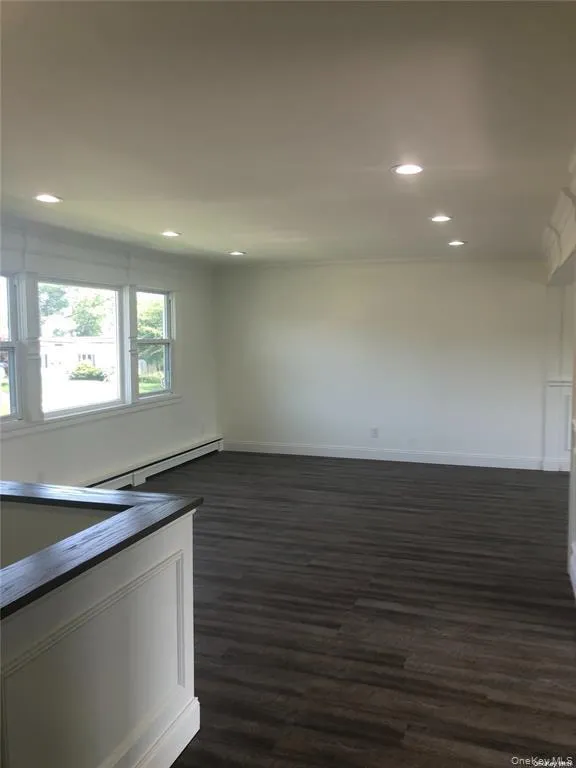 Spare room featuring a baseboard radiator, dark wood finished floors, and recessed lighting Spare room featuring a baseboard radiator, dark wood finished floors, and recessed lighting