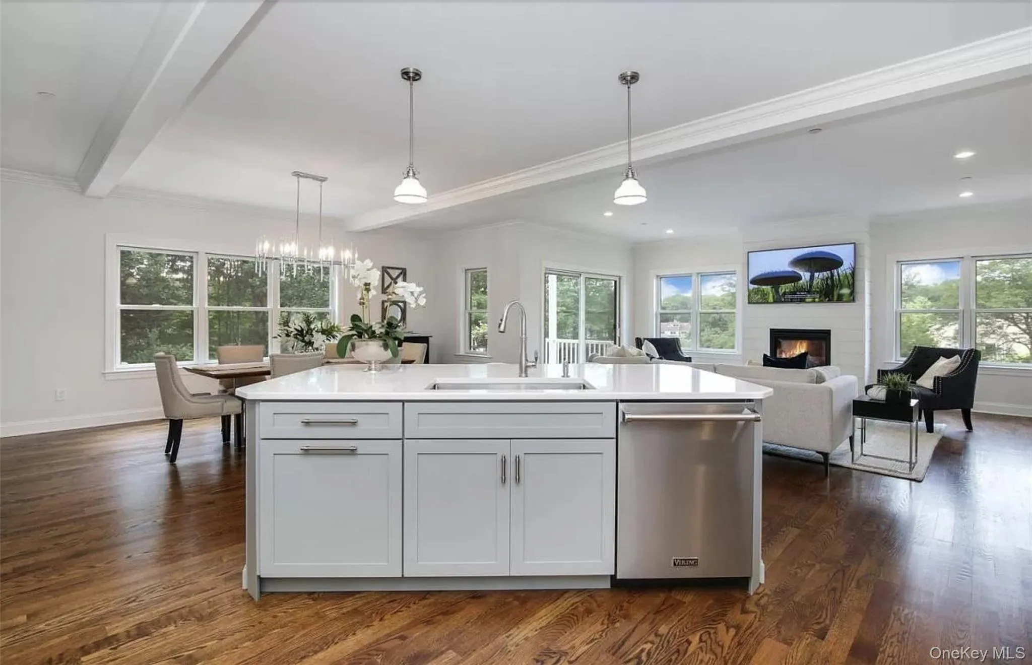 Kitchen with a large fireplace, stainless steel dishwasher, decorative light fixtures, dark wood-style flooring, and ornamental molding Kitchen with a large fireplace, stainless steel dishwasher, decorative light fixtures, dark wood-style flooring, and ornamental molding
