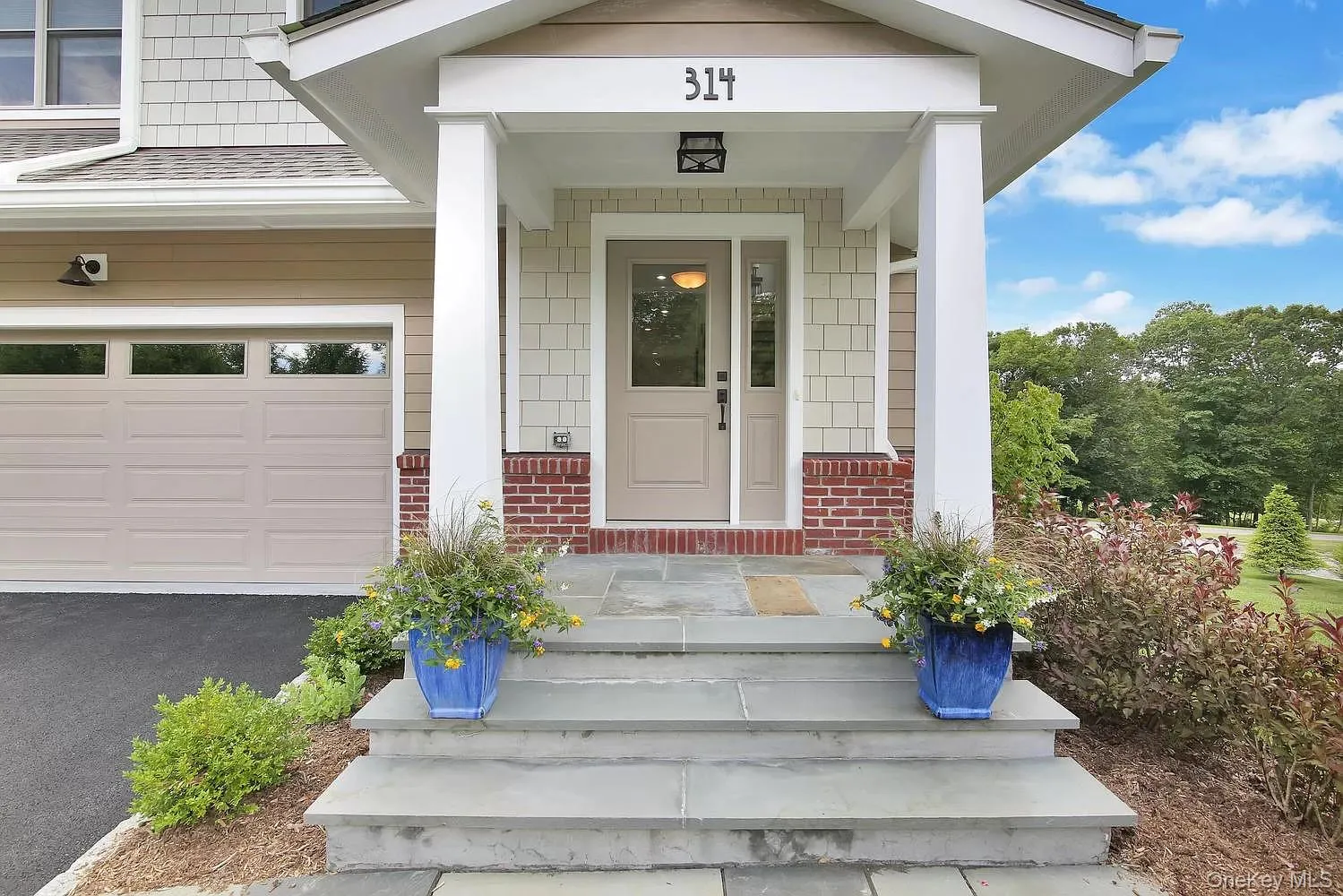 Doorway to property featuring a garage, a porch, roof with shingles, and brick siding Doorway to property featuring a garage, a porch, roof with shingles, and brick siding