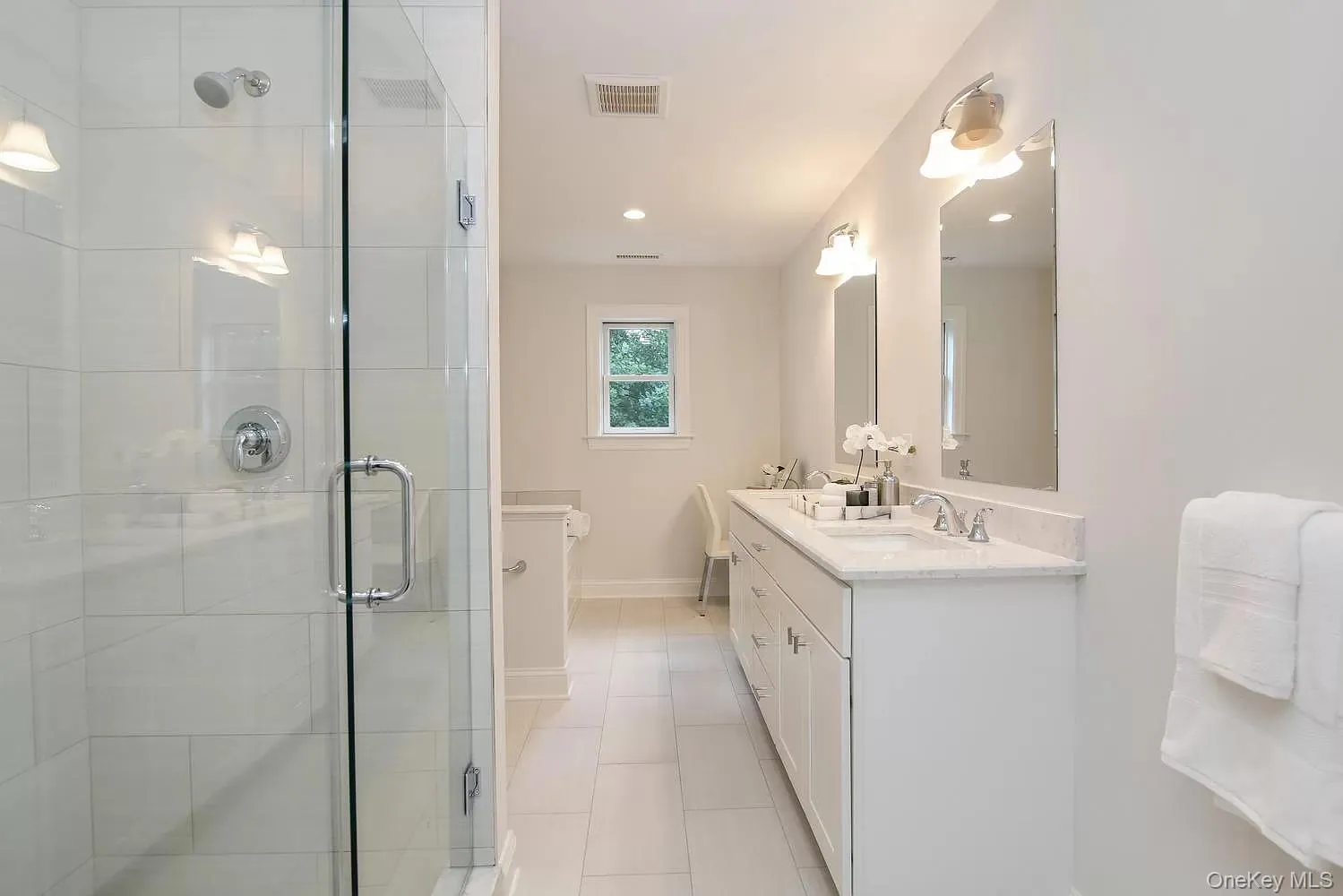 Full bath with double vanity, a stall shower, light tile patterned floors, and recessed lighting Full bath with double vanity, a stall shower, light tile patterned floors, and recessed lighting