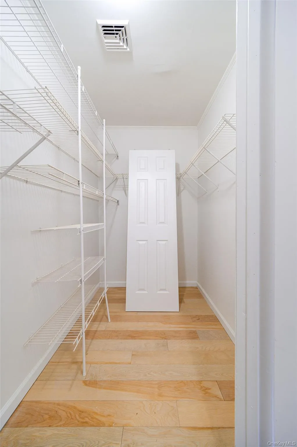Walk in closet with light wood-style flooring. Walk in closet with light wood-style flooring.