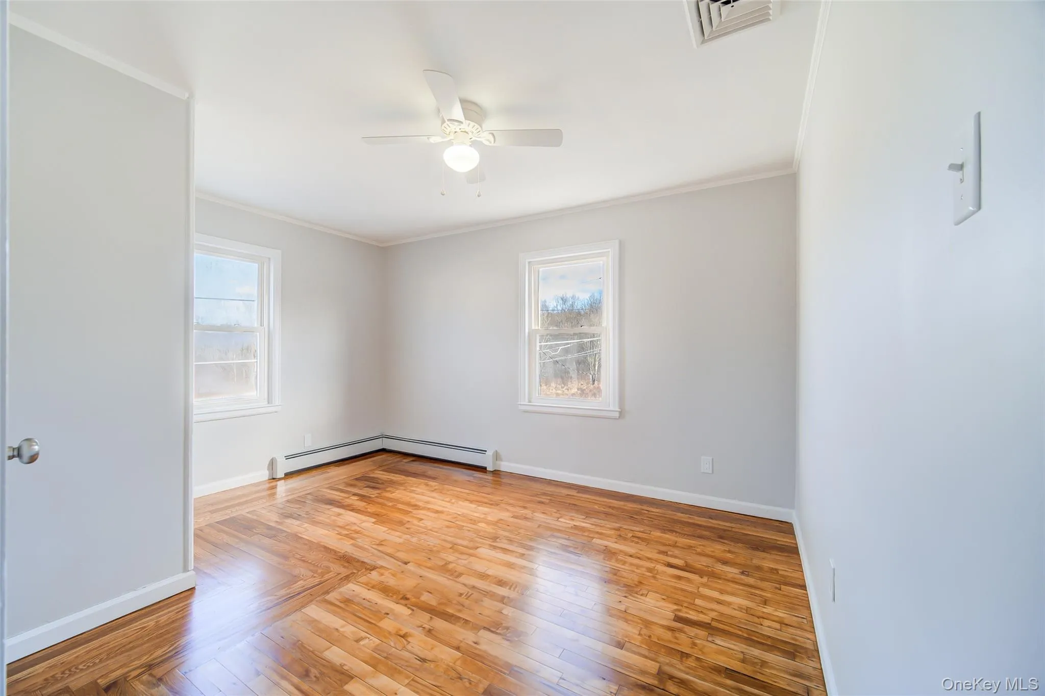 Bedroom featuring ornamental molding, light wood finished floors, healthy amount of natural light, and a ceiling fan Bedroom featuring ornamental molding, light wood finished floors, healthy amount of natural light, and a ceiling fan