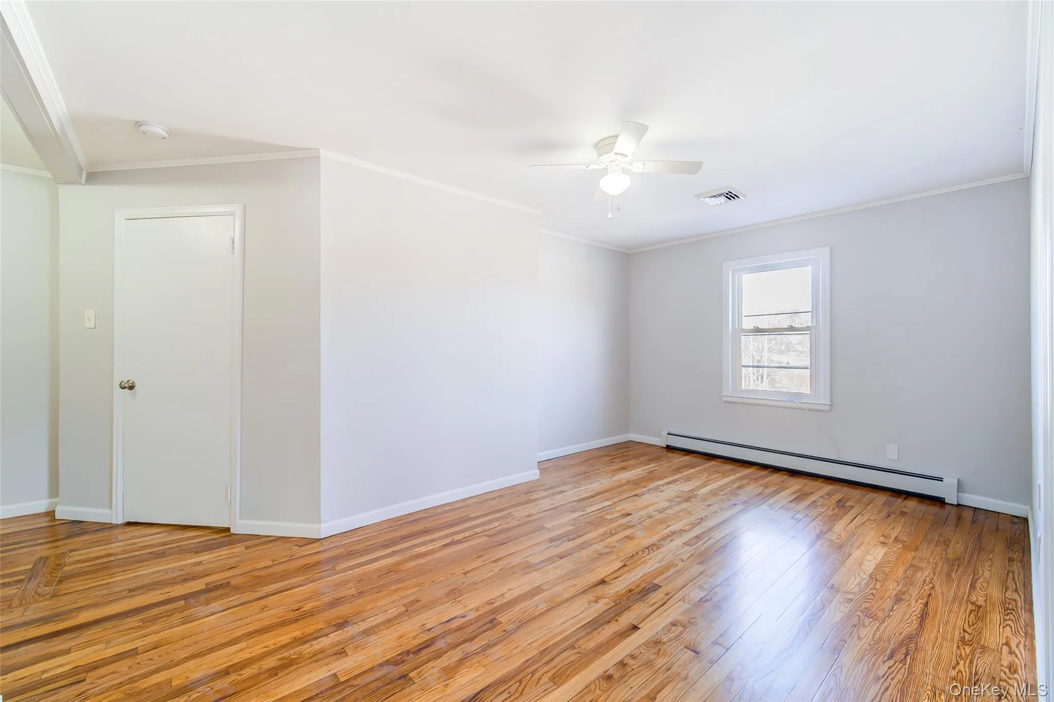 Living room with ornamental molding, light wood-style floors, a baseboard heating unit, and a ceiling fan Living room with ornamental molding, light wood-style floors, a baseboard heating unit, and a ceiling fan