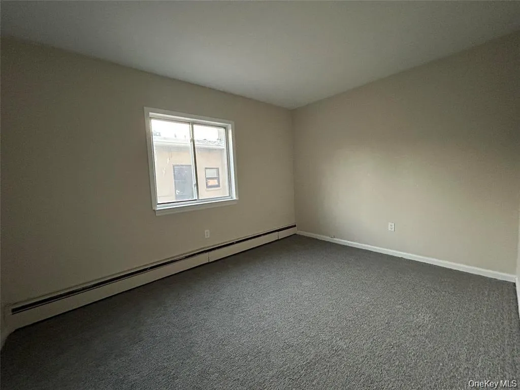 Carpeted empty room with a baseboard radiator and baseboards Carpeted empty room with a baseboard radiator and baseboards