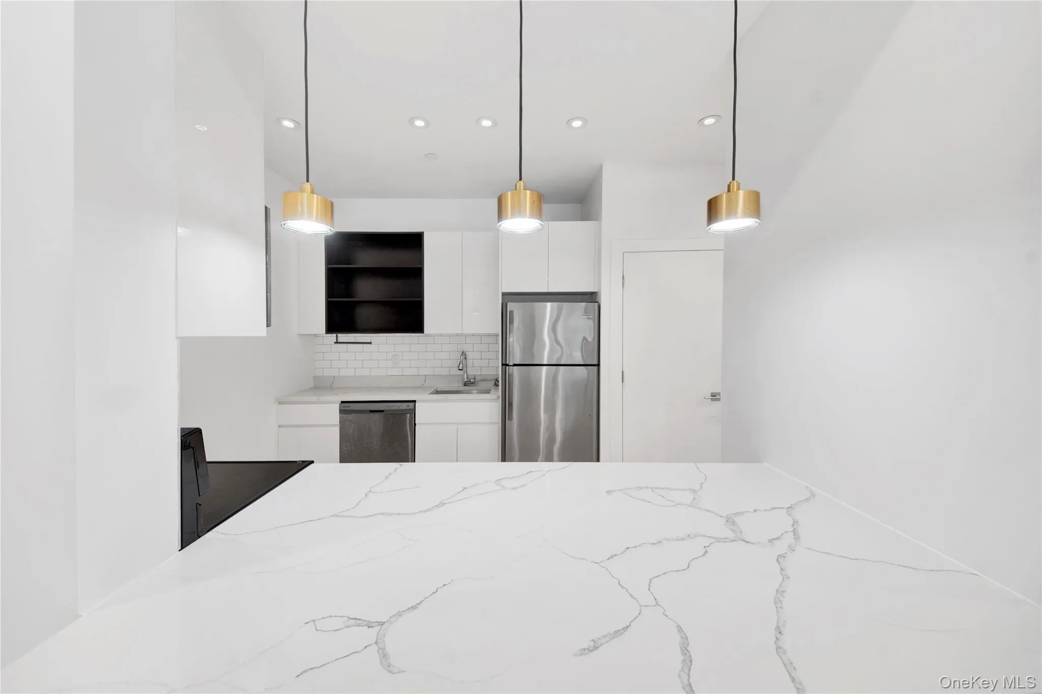 Kitchen featuring white cabinets, tasteful backsplash, decorative light fixtures, light stone countertops, and appliances with stainless steel finishes Kitchen featuring white cabinets, tasteful backsplash, decorative light fixtures, light stone countertops, and appliances with stainless steel finishes