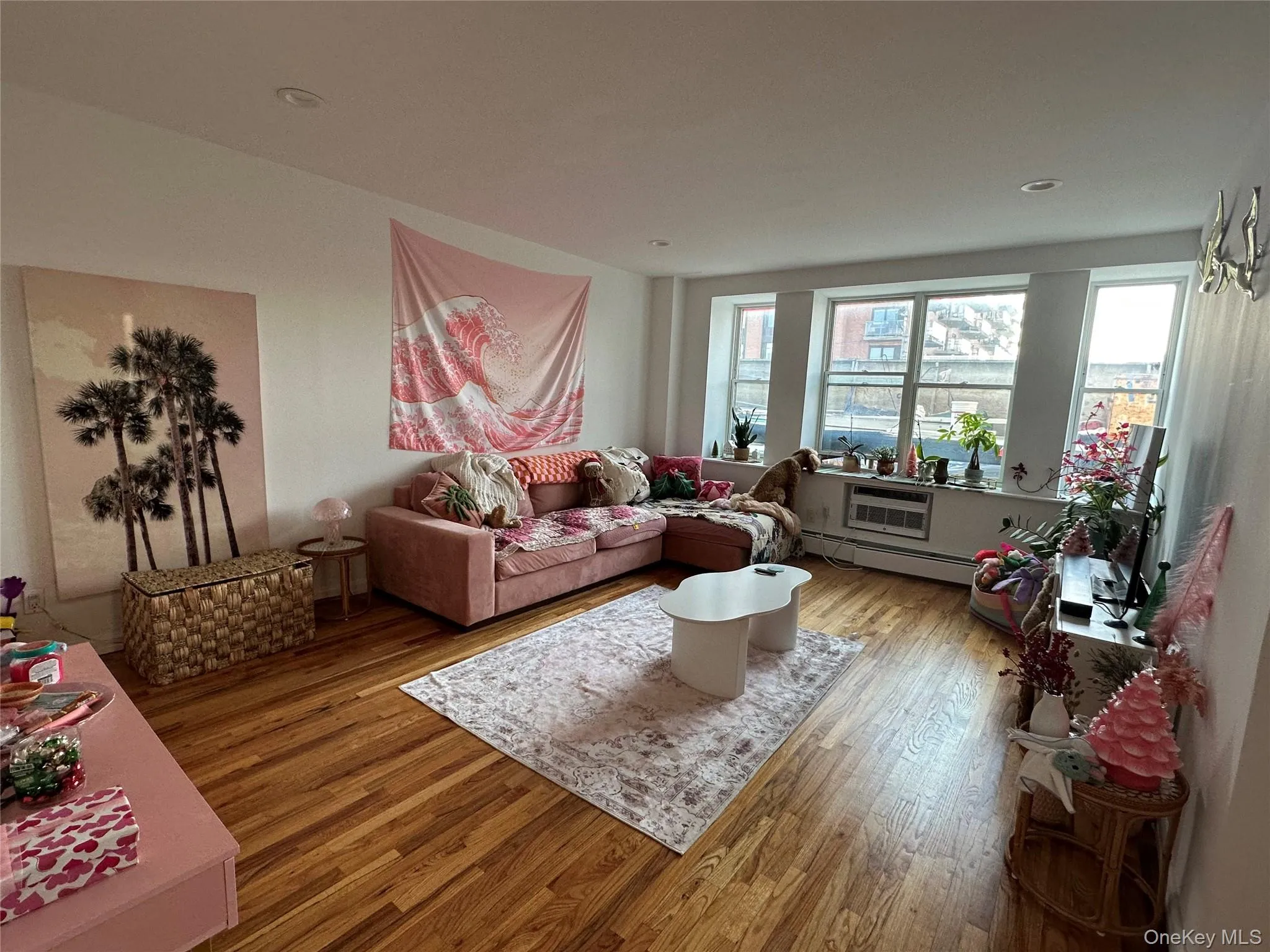 Living room featuring hardwood / wood-style flooring, baseboard heating, and a wall mounted AC Living room featuring hardwood / wood-style flooring, baseboard heating, and a wall mounted AC