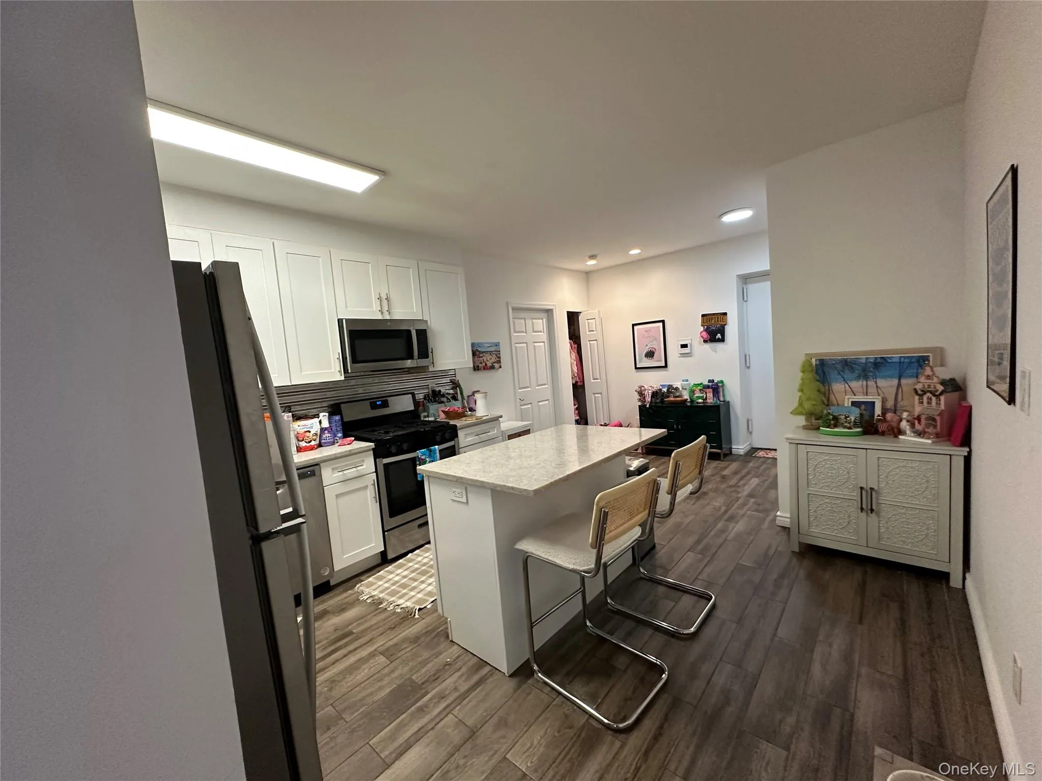 Kitchen with appliances with stainless steel finishes, white cabinets, a breakfast bar area, a kitchen island, and tasteful backsplash Kitchen with appliances with stainless steel finishes, white cabinets, a breakfast bar area, a kitchen island, and tasteful backsplash