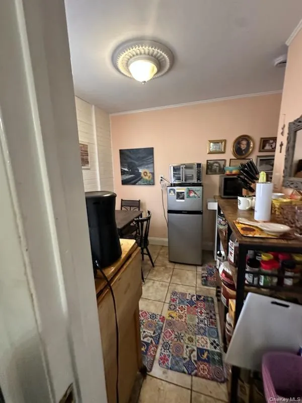 Kitchen featuring freestanding refrigerator, light tile patterned floors, and crown molding Kitchen featuring freestanding refrigerator, light tile patterned floors, and crown molding