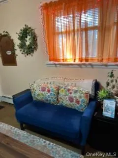 Living area with dark wood-style floors and baseboard heating Living area with dark wood-style floors and baseboard heating