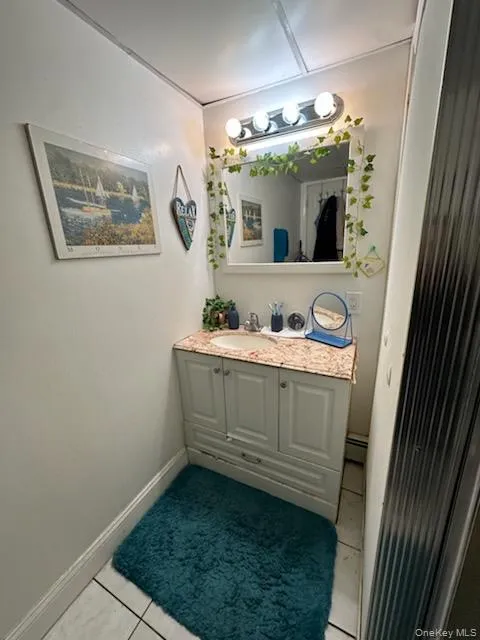 Bathroom with vanity, light tile patterned flooring, and a baseboard radiator Bathroom with vanity, light tile patterned flooring, and a baseboard radiator