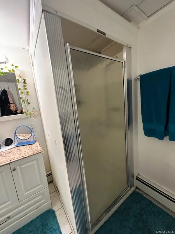 Bathroom featuring a baseboard heating unit and a shower stall Bathroom featuring a baseboard heating unit and a shower stall