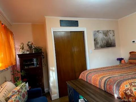 Bedroom featuring crown molding and a closet Bedroom featuring crown molding and a closet