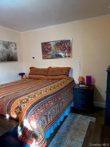 Bedroom featuring ornamental molding and wood finished floors Bedroom featuring ornamental molding and wood finished floors