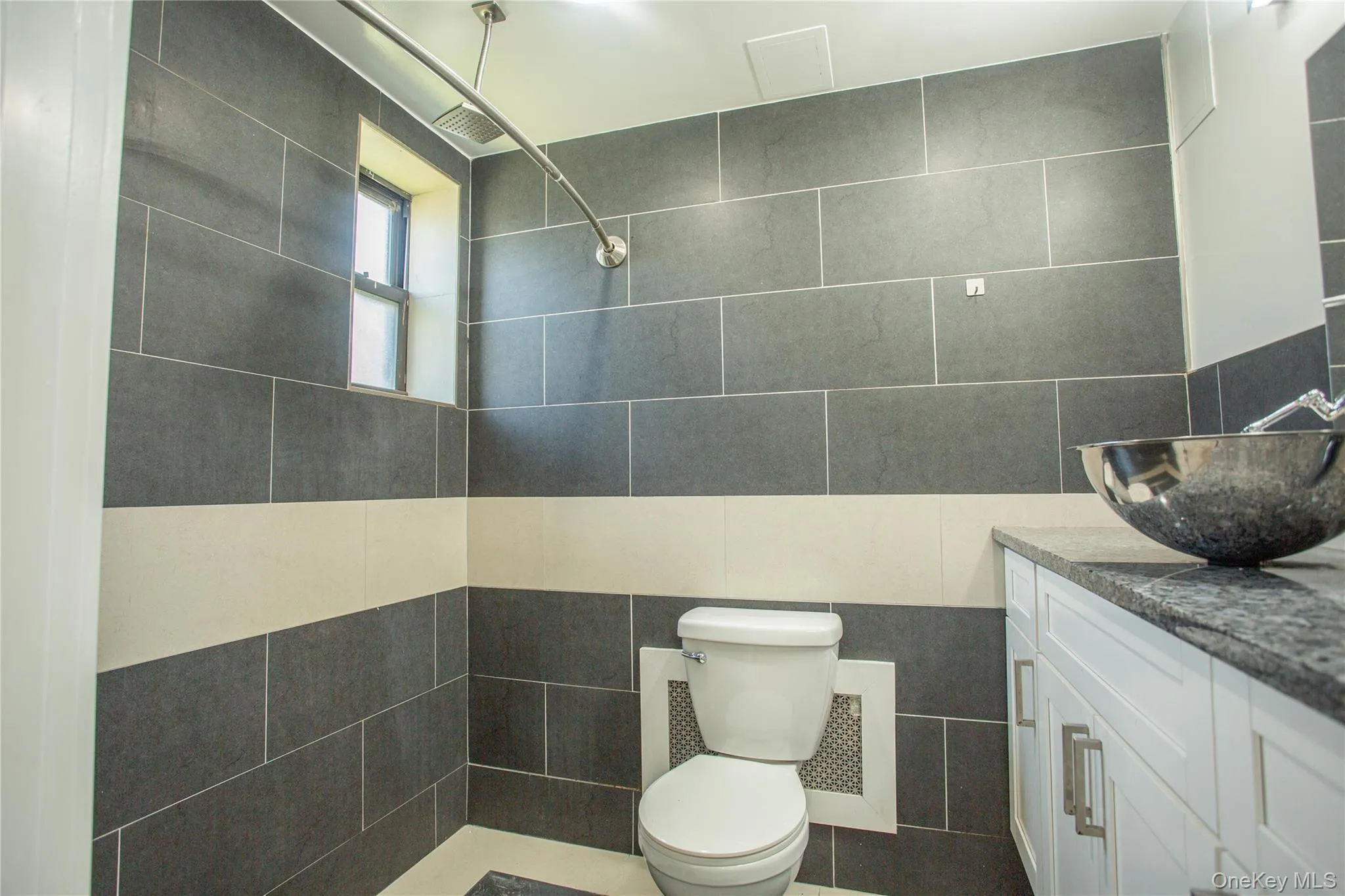 Full bathroom featuring tile walls, vanity, toilet, and tiled shower Full bathroom featuring tile walls, vanity, toilet, and tiled shower