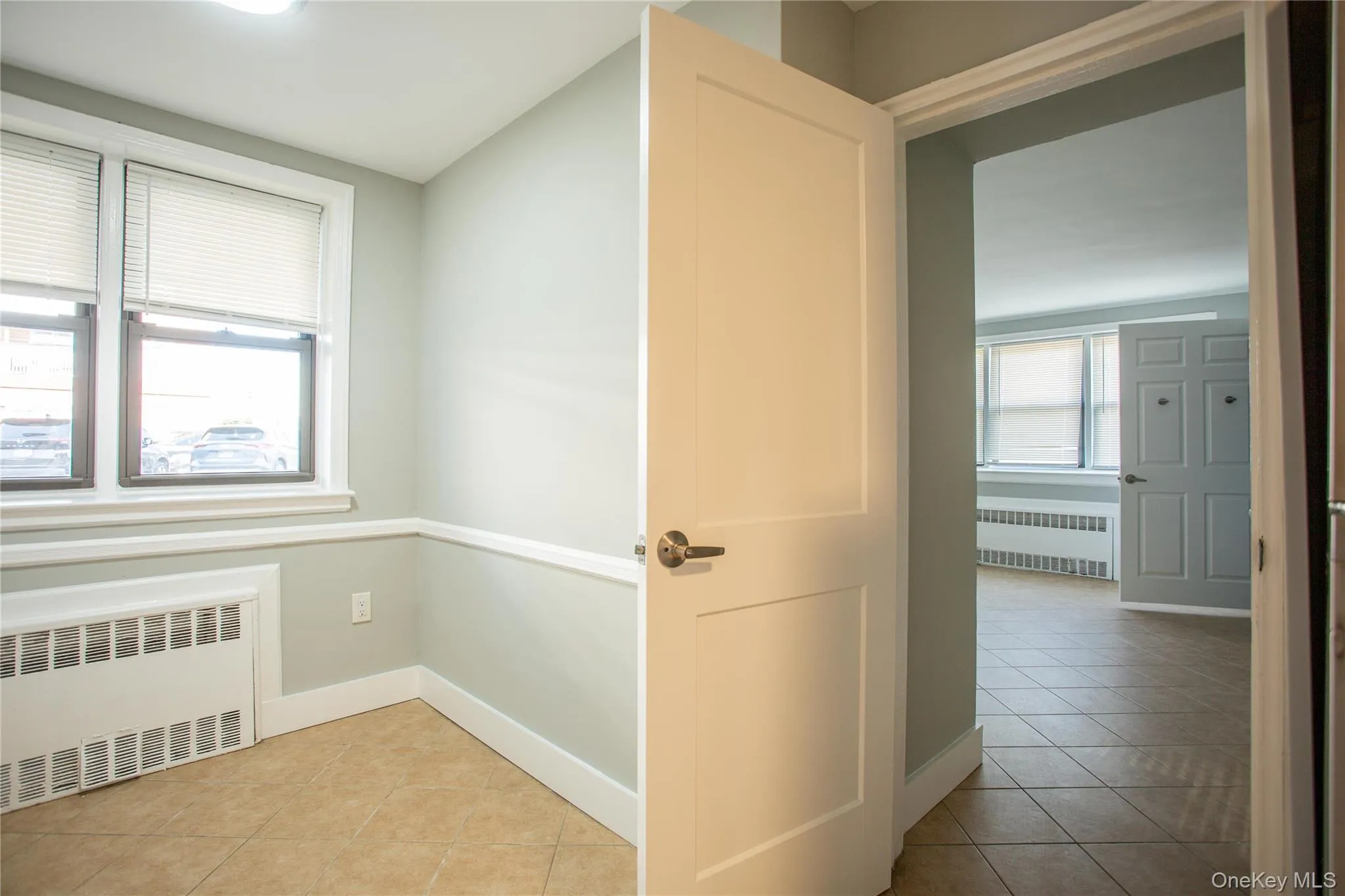 Hall with radiator, light tile patterned floors, and baseboards Hall with radiator, light tile patterned floors, and baseboards