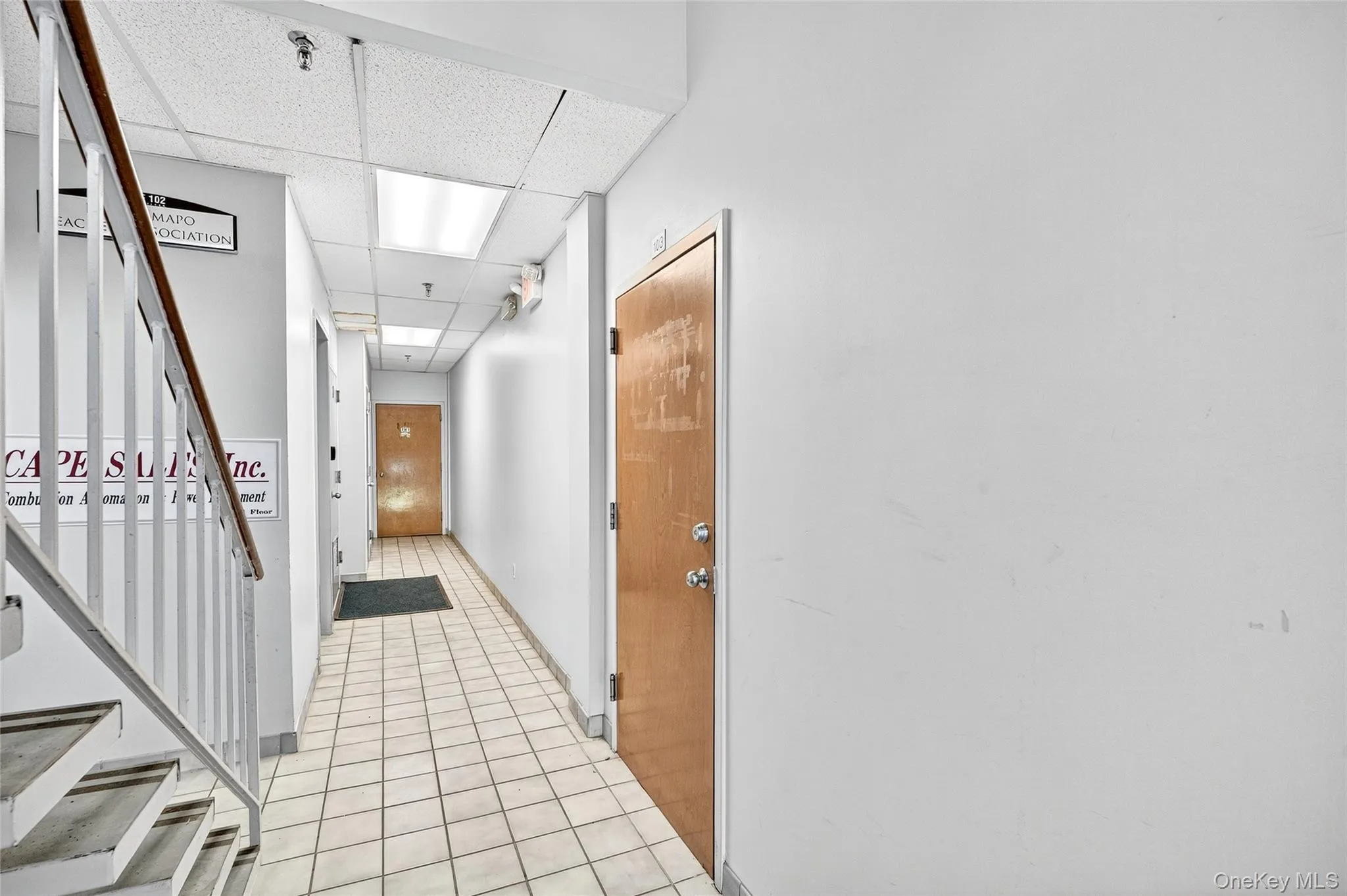 Hall with light tile patterned floors, a paneled ceiling, and stairway Hall with light tile patterned floors, a paneled ceiling, and stairway