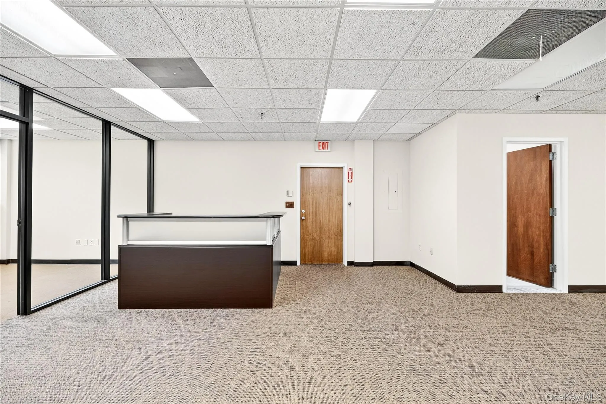 Empty room with a paneled ceiling and light colored carpet Empty room with a paneled ceiling and light colored carpet