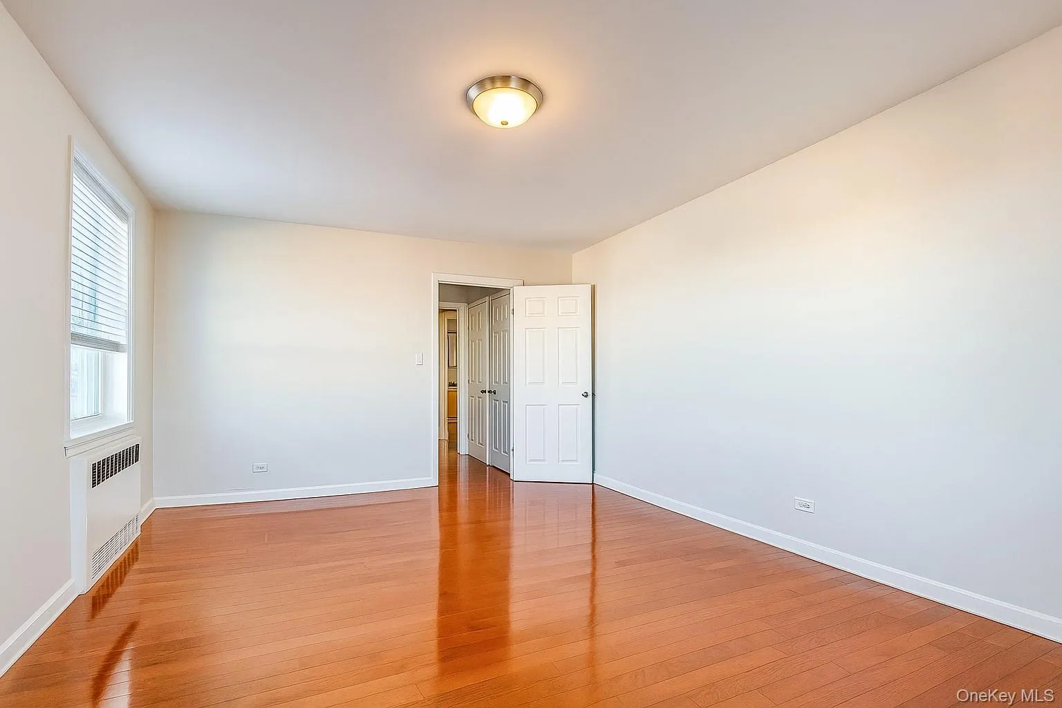 Unfurnished bedroom featuring light wood-type flooring and radiator heating unit Unfurnished bedroom featuring light wood-type flooring and radiator heating unit