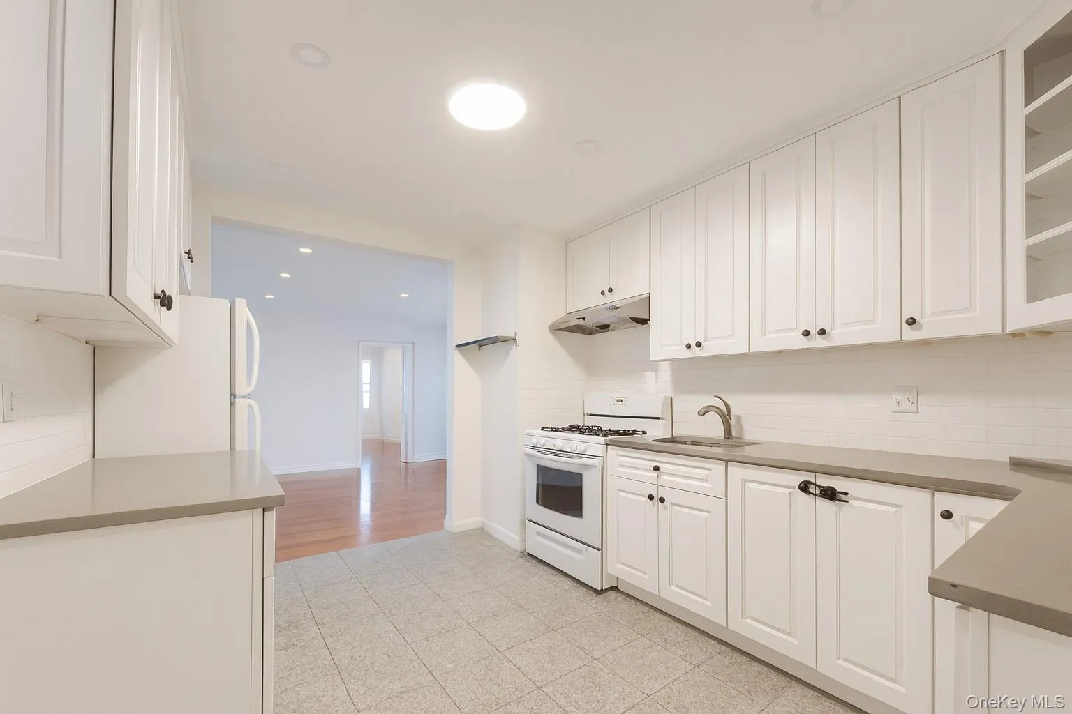 Kitchen featuring white appliances, white cabinetry, tasteful backsplash, and recessed lighting Kitchen featuring white appliances, white cabinetry, tasteful backsplash, and recessed lighting