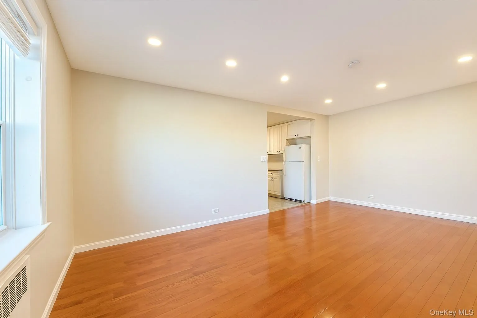 Empty room featuring light wood-style floors, recessed lighting, and radiator heating unit Empty room featuring light wood-style floors, recessed lighting, and radiator heating unit