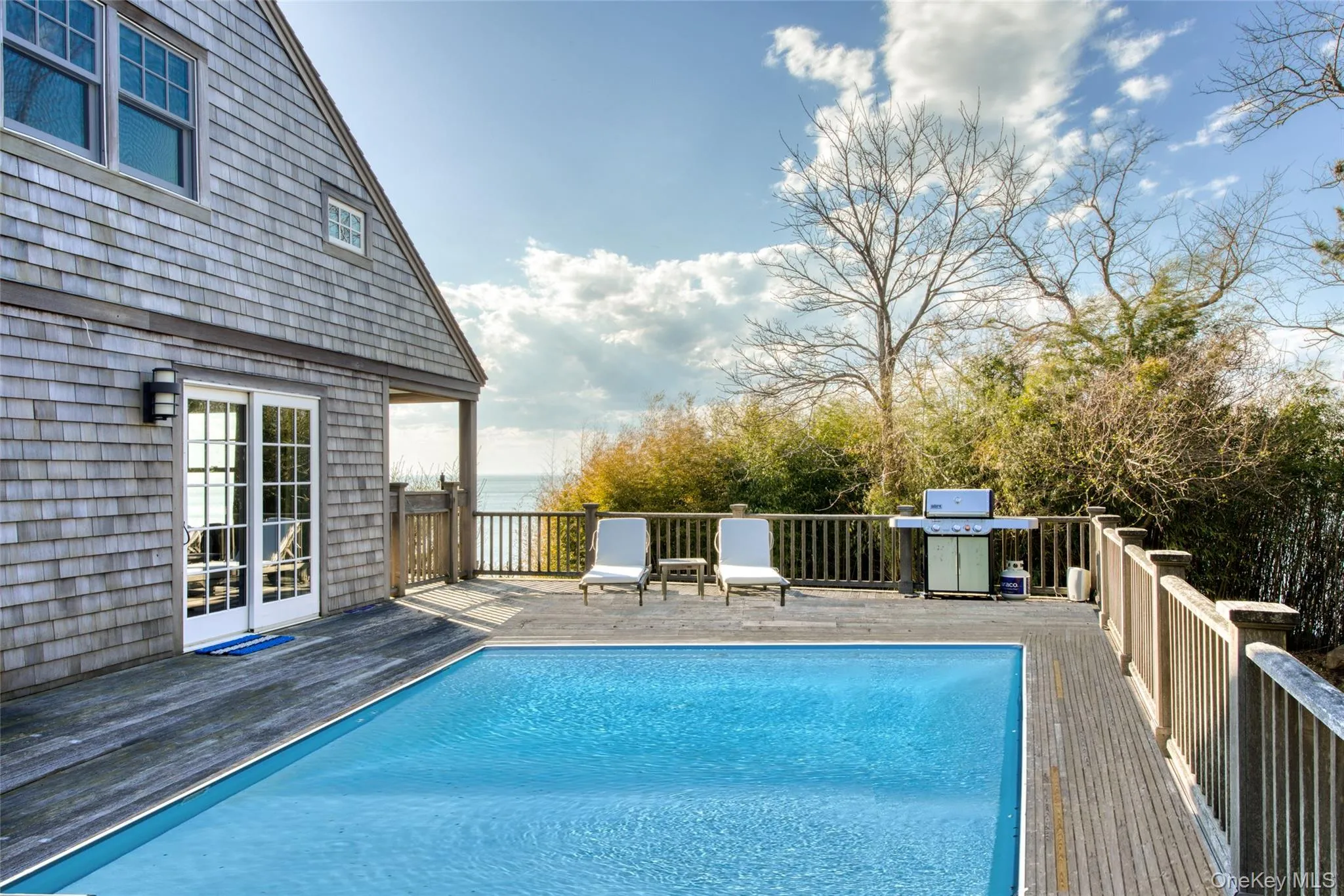 View of swimming pool featuring area for grilling and a wooden deck View of swimming pool featuring area for grilling and a wooden deck