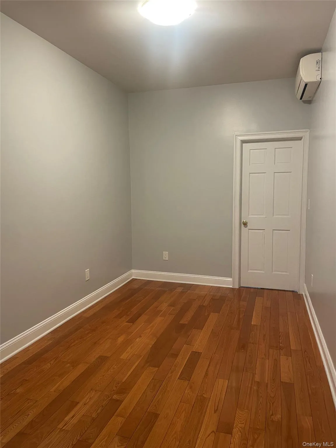 Unfurnished room featuring dark wood-style flooring and a wall unit AC Unfurnished room featuring dark wood-style flooring and a wall unit AC