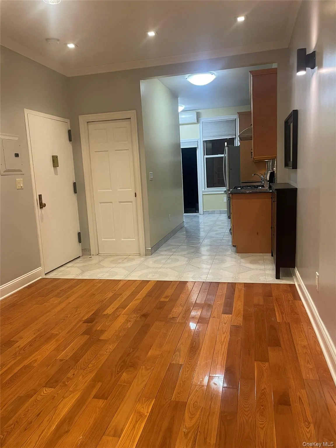 Kitchen with light wood finished floors, crown molding, brown cabinetry, dark countertops, and recessed lighting Kitchen with light wood finished floors, crown molding, brown cabinetry, dark countertops, and recessed lighting