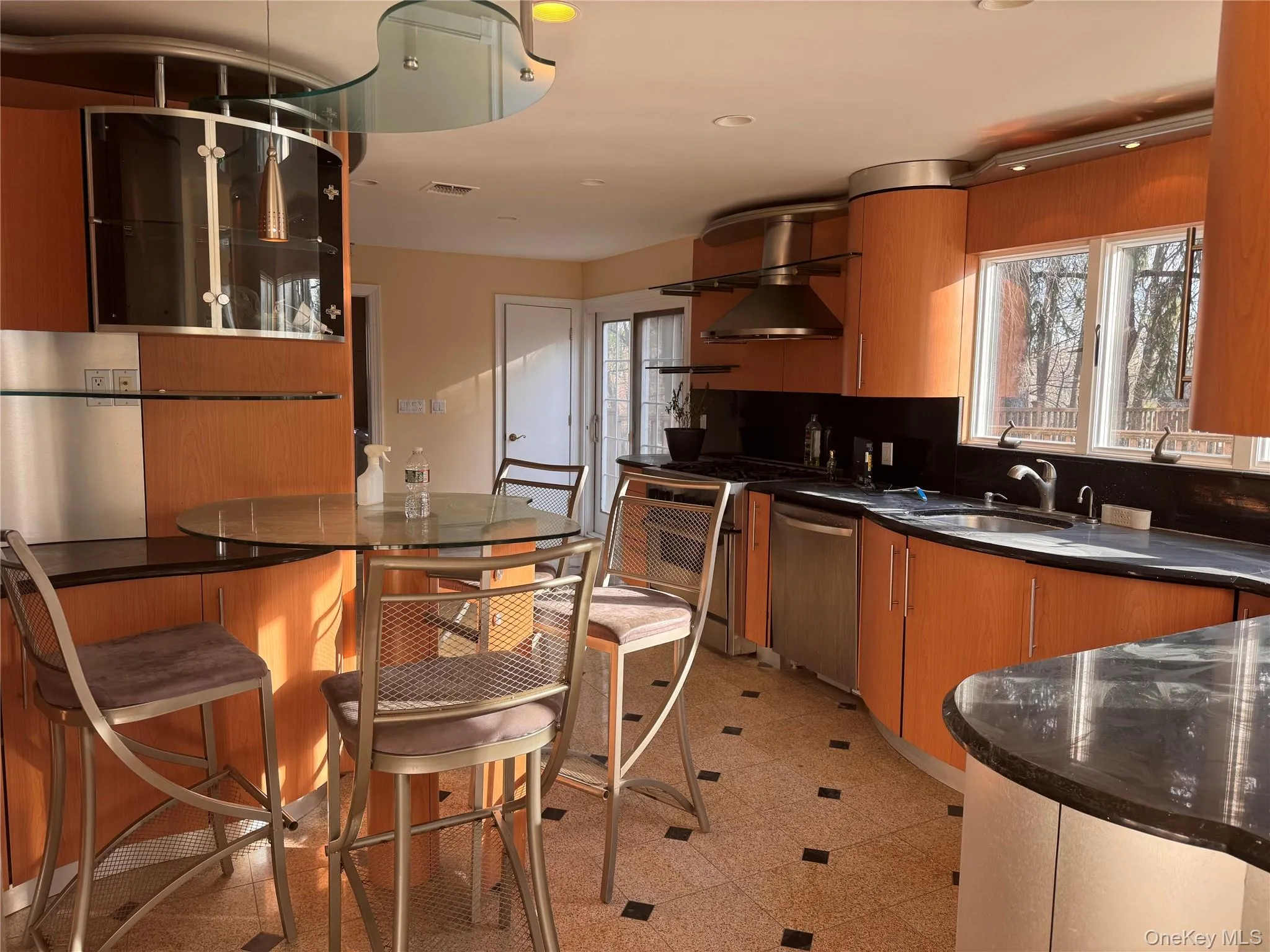 Kitchen with dark stone counters, dishwasher, backsplash, wall chimney exhaust hood, and modern cabinets Kitchen with dark stone counters, dishwasher, backsplash, wall chimney exhaust hood, and modern cabinets