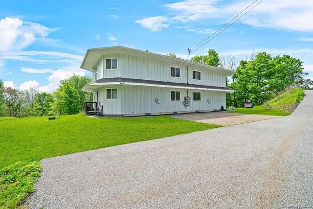 View of front of property featuring board and batten siding, a front yard, and driveway View of front of property featuring board and batten siding, a front yard, and driveway