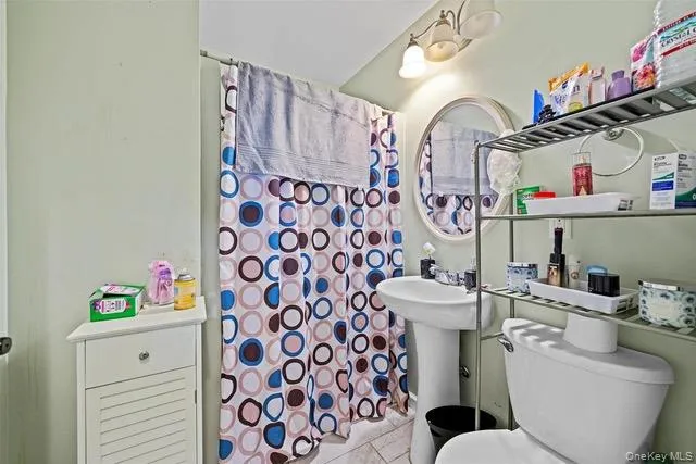Bathroom featuring a shower with curtain and light tile patterned floors Bathroom featuring a shower with curtain and light tile patterned floors