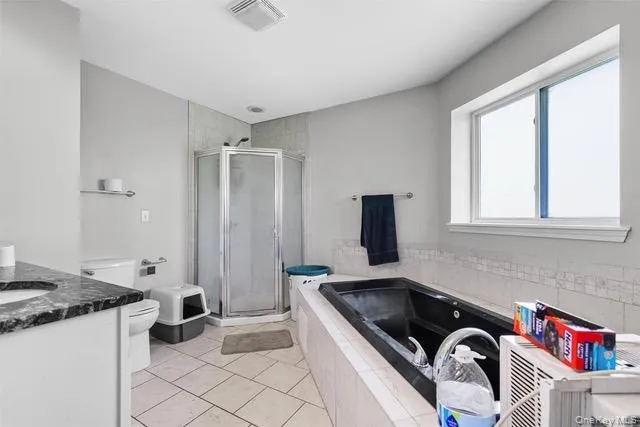 Bathroom with vanity, a shower stall, light tile patterned floors, and a garden tub Bathroom with vanity, a shower stall, light tile patterned floors, and a garden tub