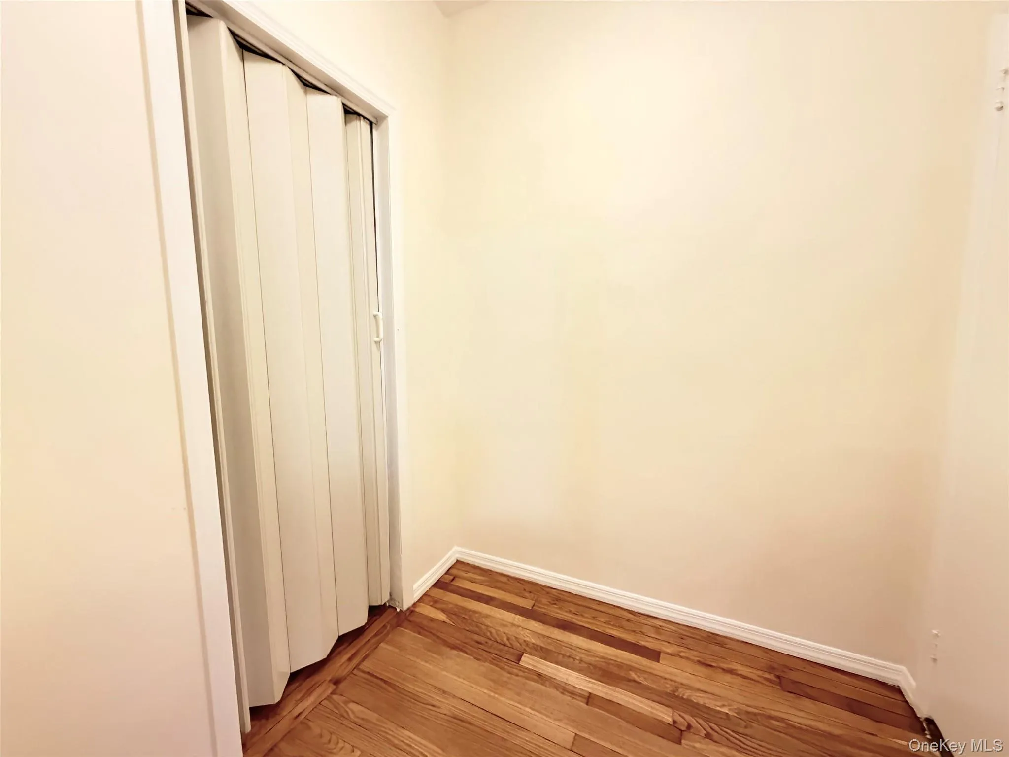 Unfurnished bedroom with wood-type flooring and a closet Unfurnished bedroom with wood-type flooring and a closet