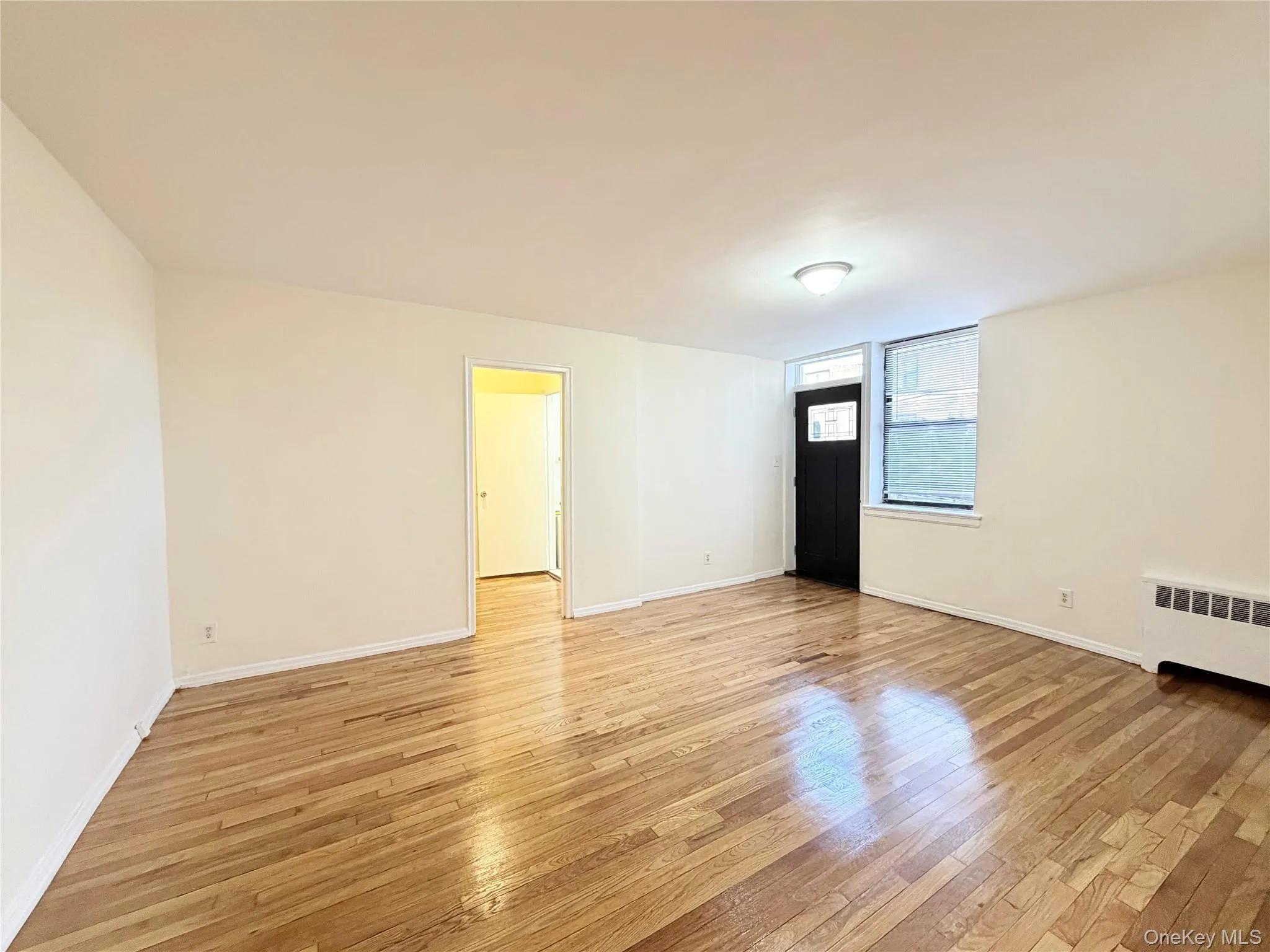 Unfurnished room with light wood-type flooring and radiator heating unit Unfurnished room with light wood-type flooring and radiator heating unit