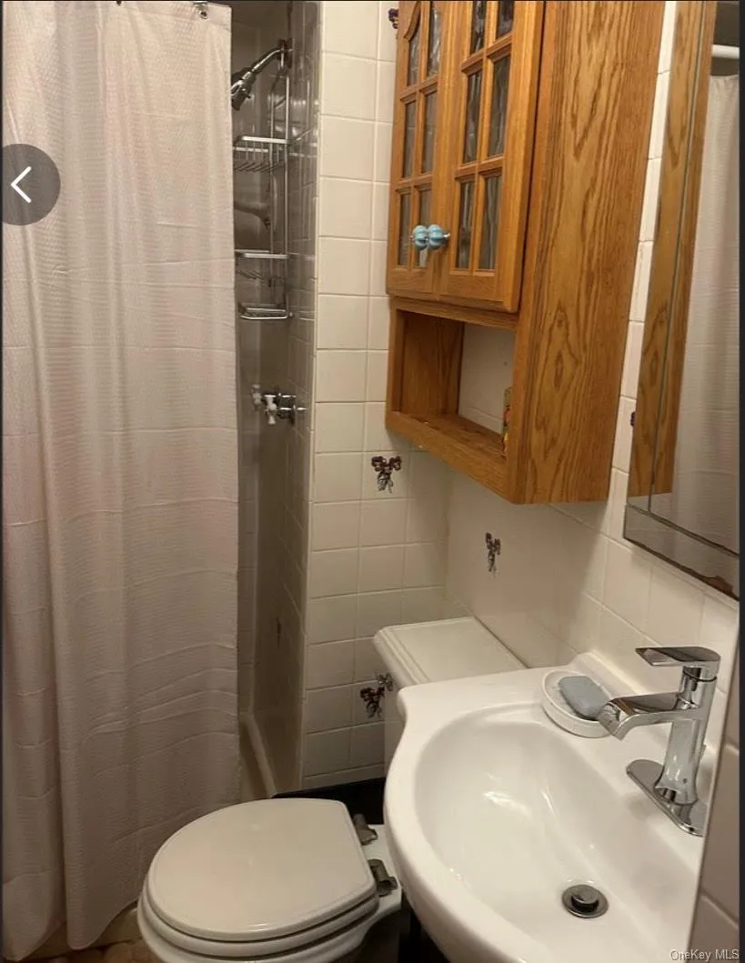 Full bathroom with a shower with curtain, tasteful backsplash, and tile walls Full bathroom with a shower with curtain, tasteful backsplash, and tile walls