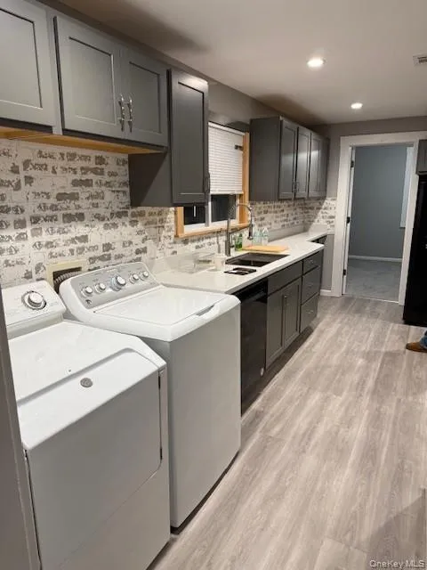 Laundry room with light wood-style flooring, washer and clothes dryer, and recessed lighting Laundry room with light wood-style flooring, washer and clothes dryer, and recessed lighting