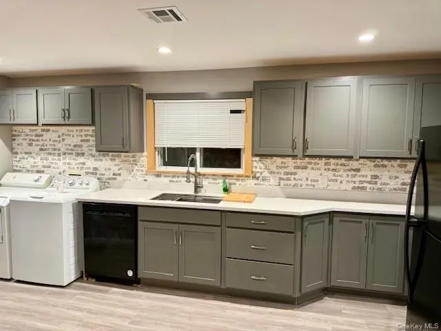 Kitchen featuring gray cabinetry, black appliances, light wood finished floors, recessed lighting, and washing machine and clothes dryer Kitchen featuring gray cabinetry, black appliances, light wood finished floors, recessed lighting, and washing machine and clothes dryer