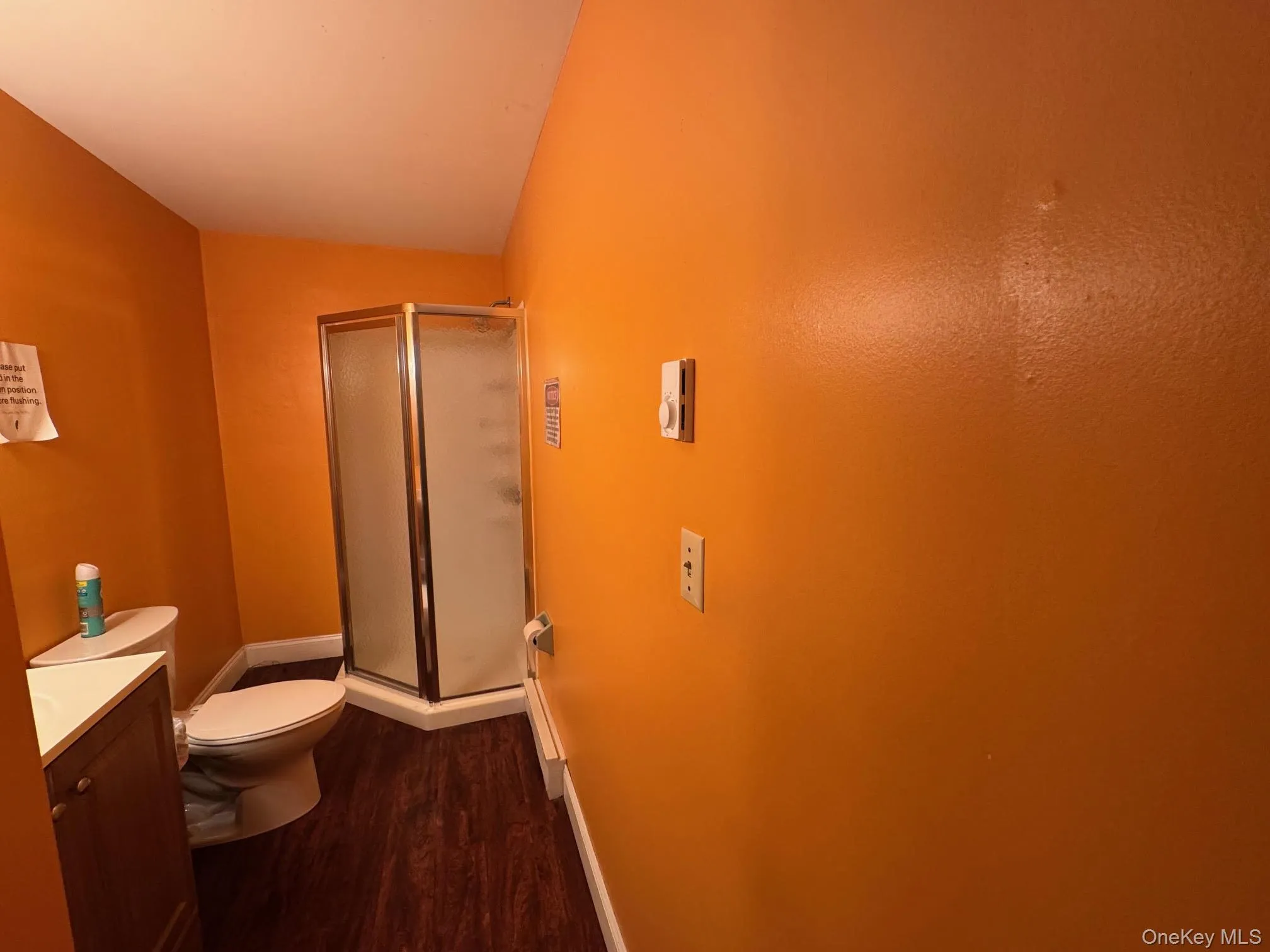 Full bath with vanity, a shower, and dark wood finished floors Full bath with vanity, a shower, and dark wood finished floors