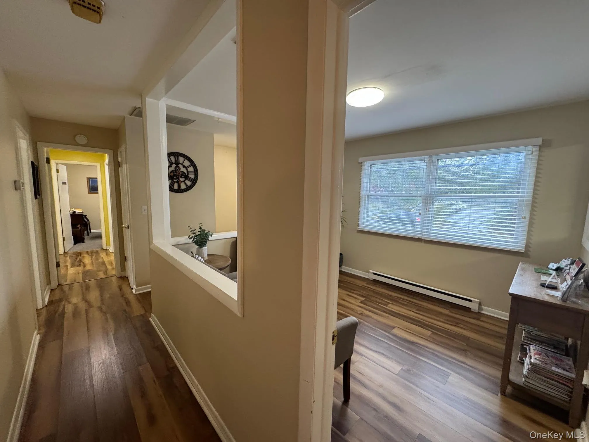 Hallway with baseboard heating and dark wood-style floors Hallway with baseboard heating and dark wood-style floors
